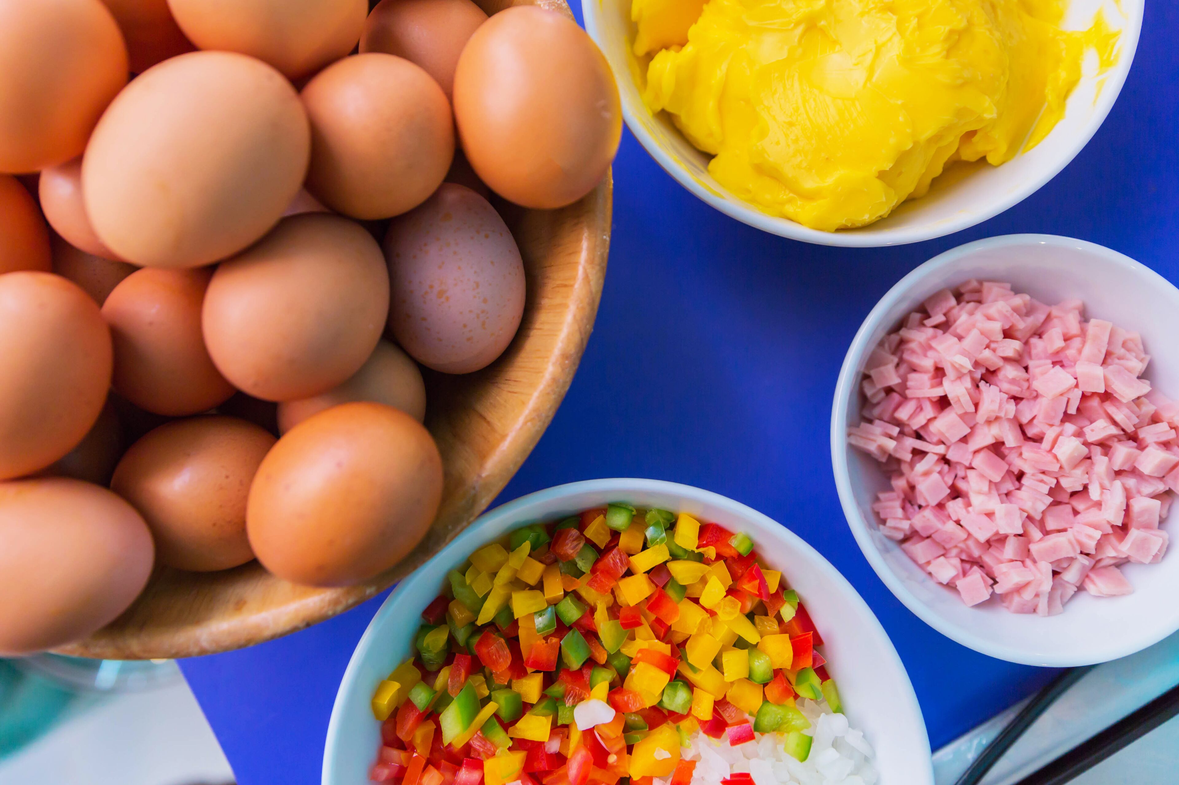 Verschiedene Lebensmittel wie Eier, gewürfelter Schinken und bunte Paprika.