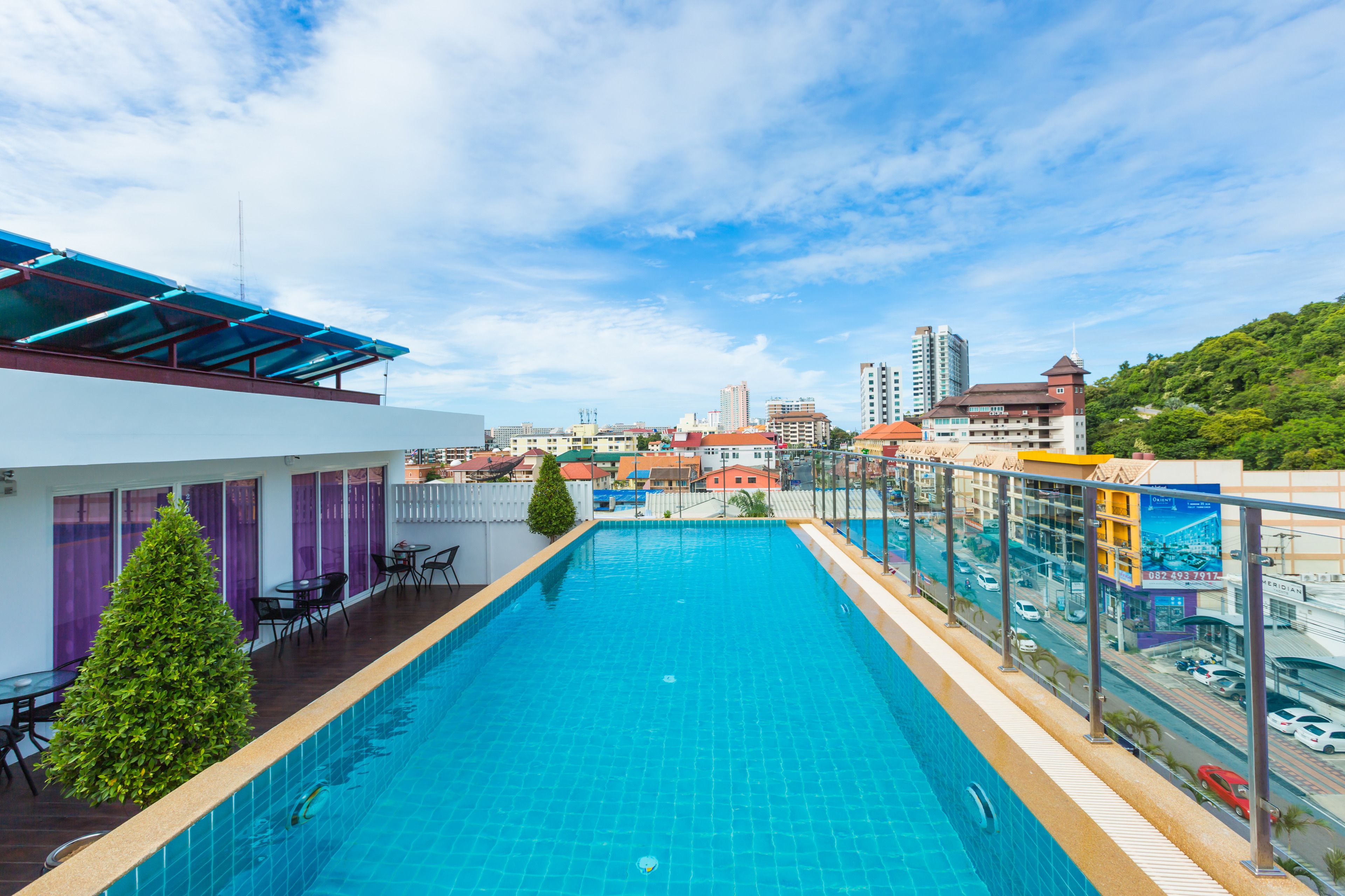 Una piscina sul tetto con vista sulla città, tra cui edifici e una collina.