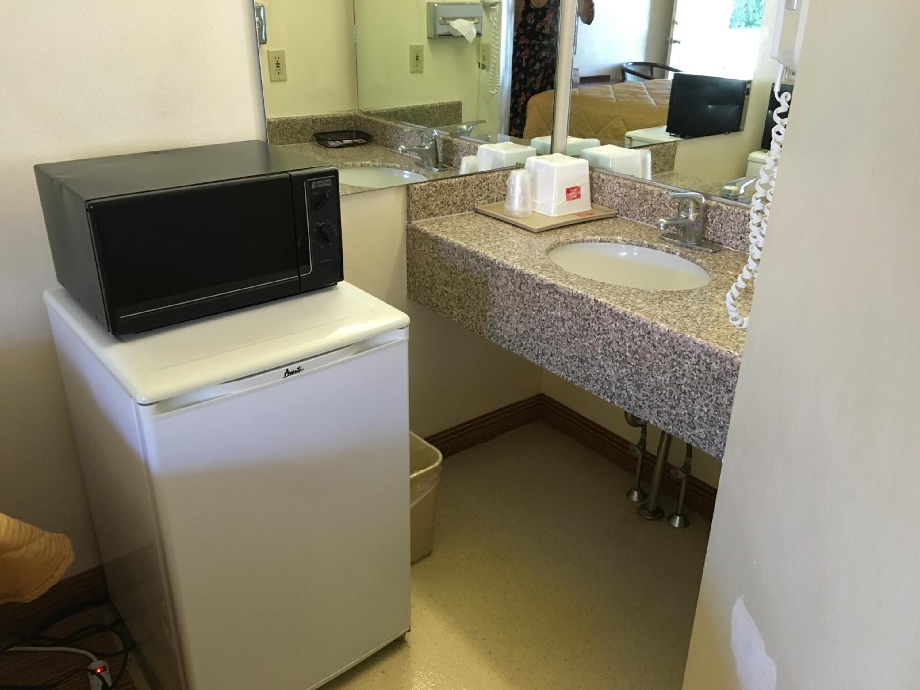 Una kitchenette compacta con microondas, pileta y mostrador.