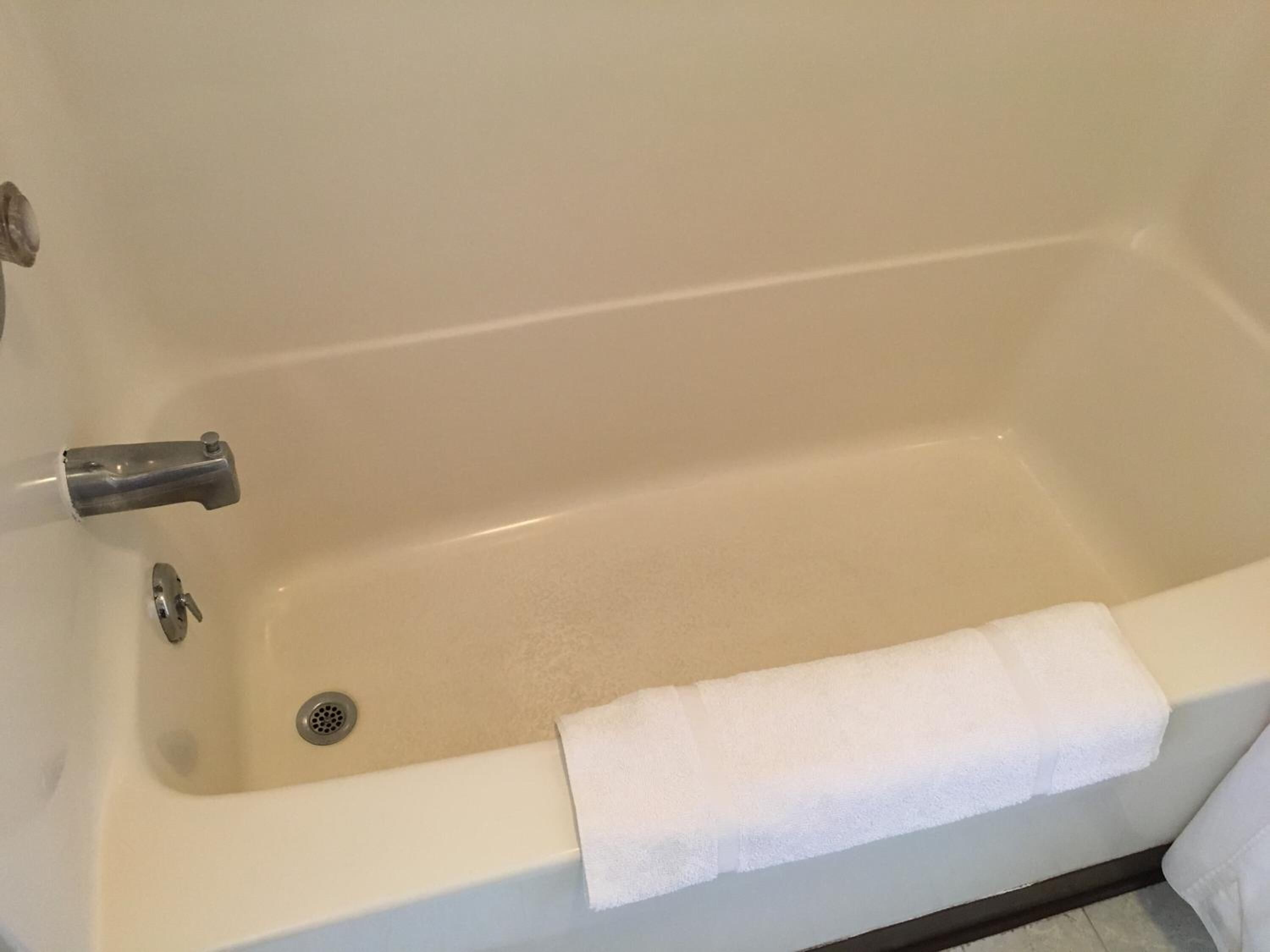 A bathtub with a white towel and a drain.
