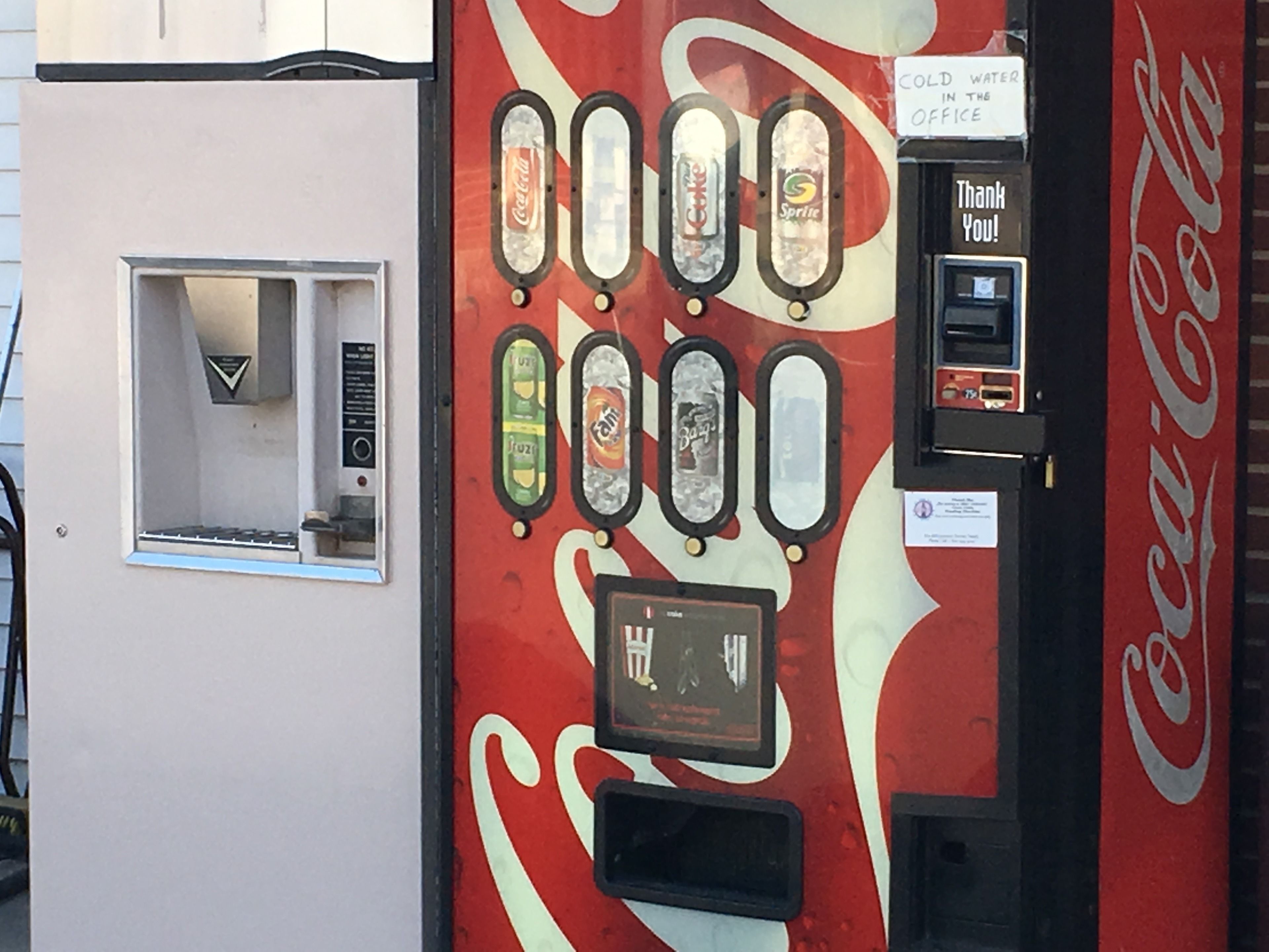 Máquina expendedora vintage de Coca-Cola con varias opciones de bebidas, ranura para monedas y un letrero que dice 'Gracias'.