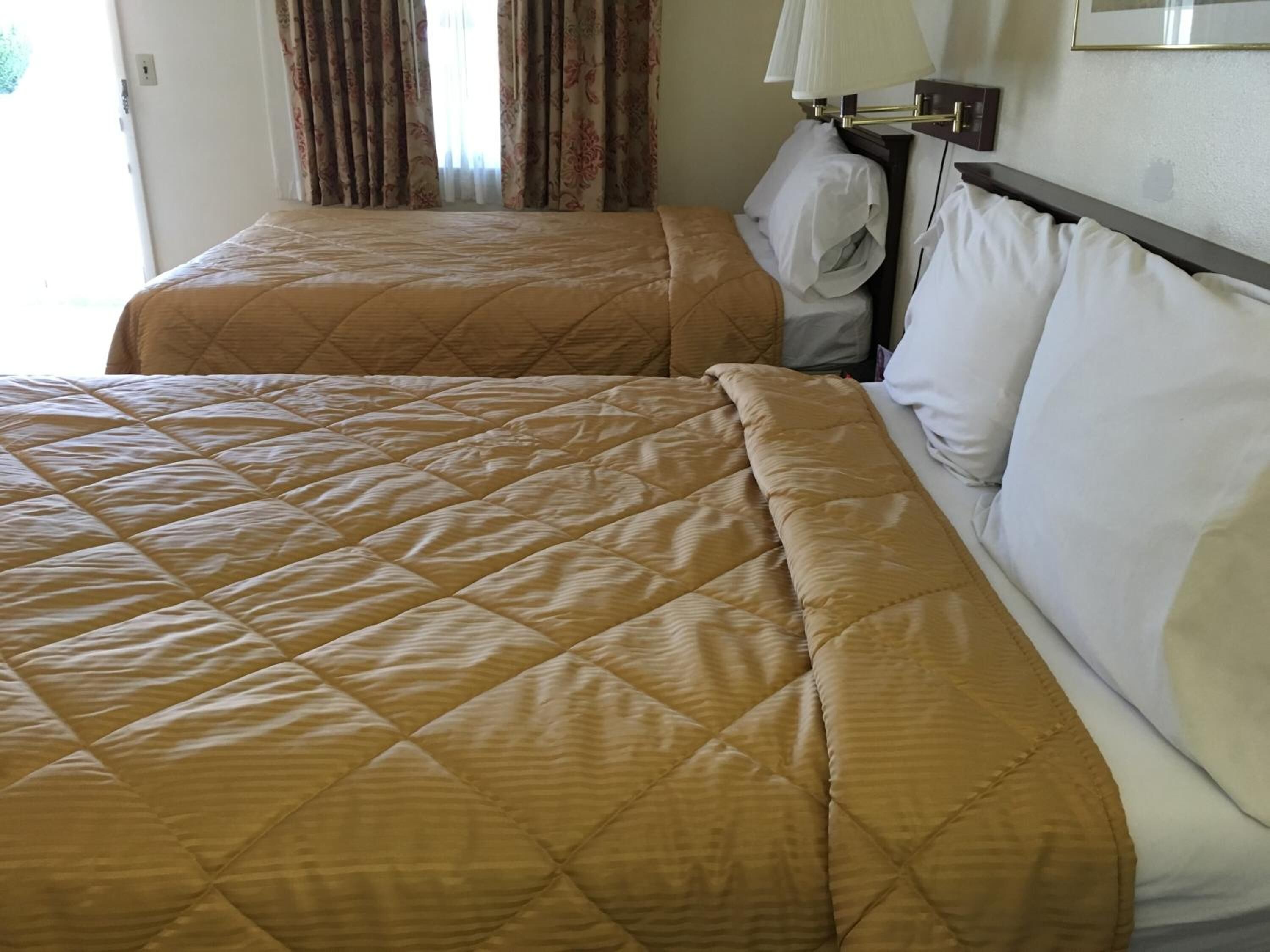 Quarto de hotel com duas camas, cada uma com colcha acolchoada e almofadas.