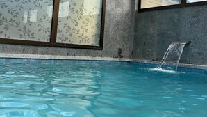 Piscina com cachoeira, emoldurada por amplas janelas com o logotipo da empresa.