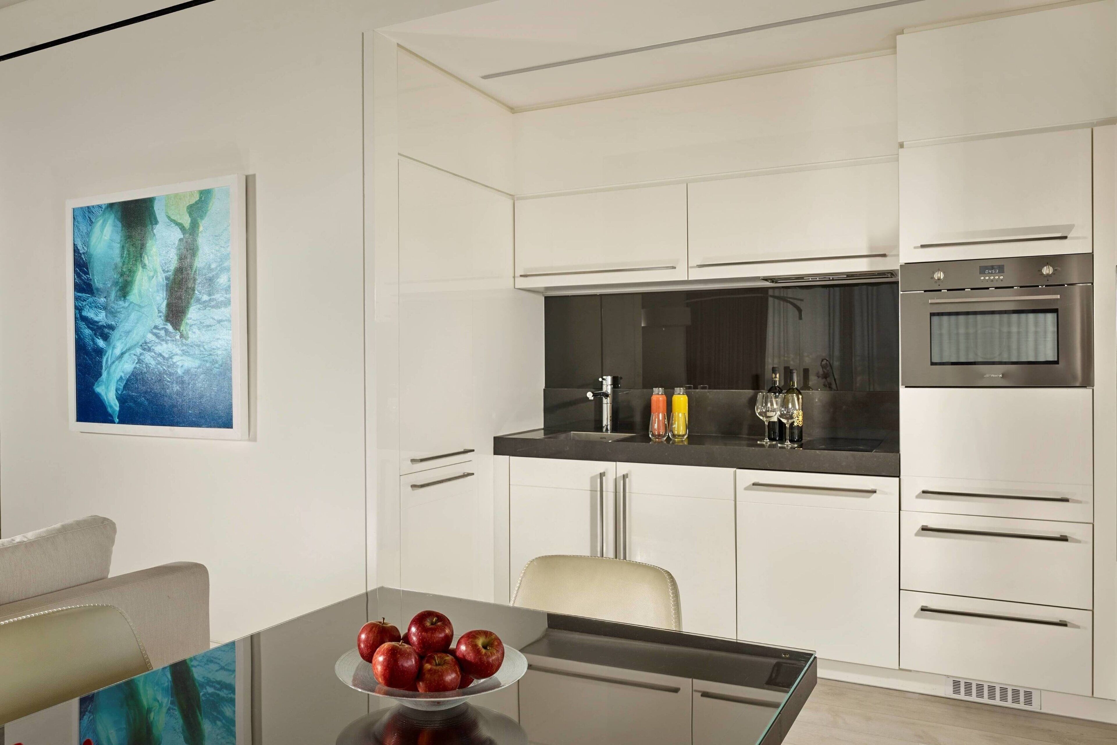 Une cuisine moderne avec des armoires blanches, un plan de travail noir et des appareils électroménagers en acier inoxydable.
