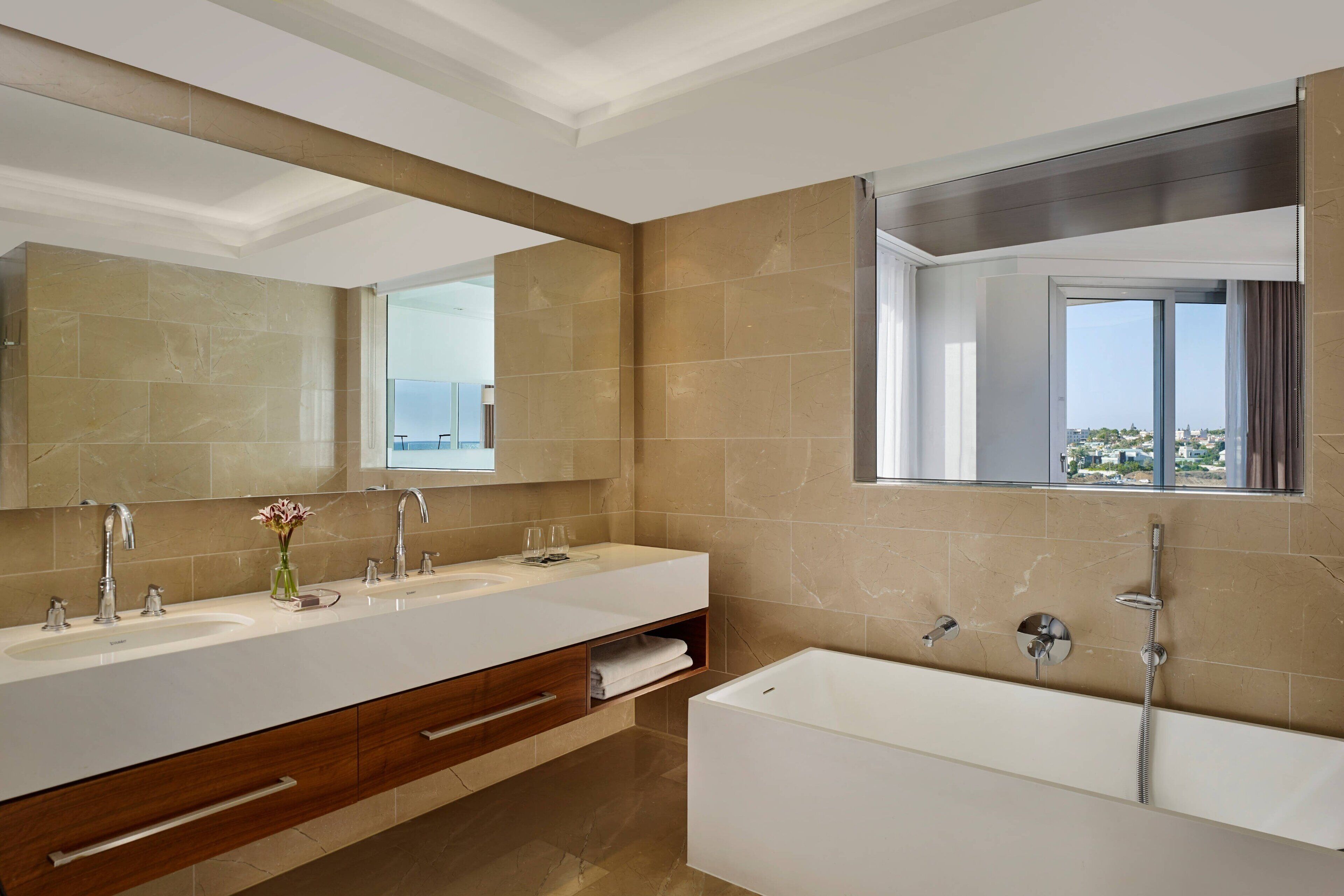 Un bagno moderno con due lavandini, uno specchio grande e una vasca da bagno.