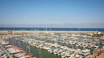 A marina with numerous boats docked, a clear sky, and a calm sea.