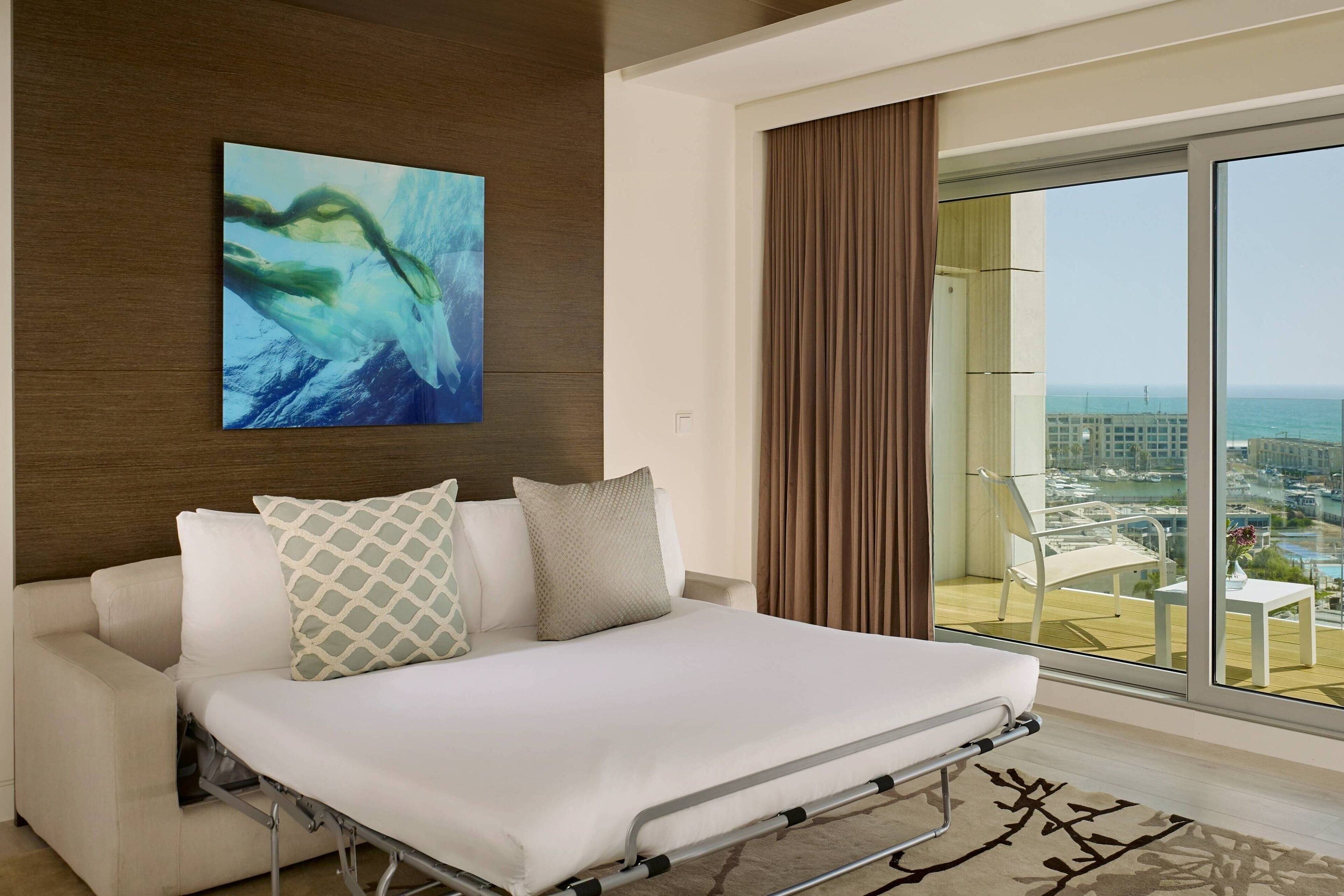 Une chambre d’hôtel moderne avec un lit, une vue sur la ville et une grande fenêtre.