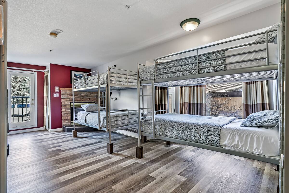 Una habitación con literas, una puerta con vistas y una ventana con cortinas.