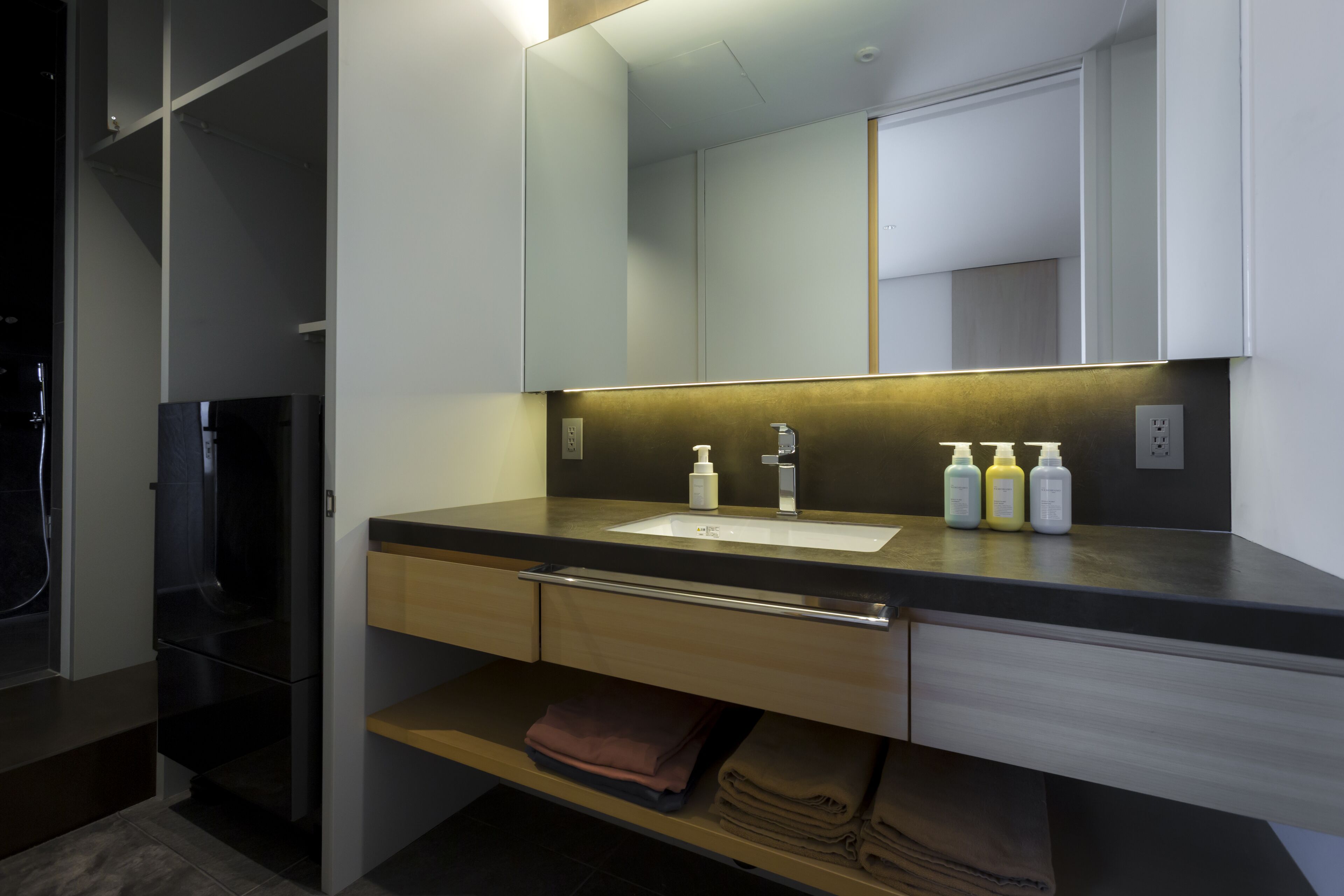 A modern bathroom with a sink, mirror, and storage shelves.
