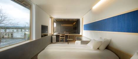 A modern hotel room with two beds, a desk, and a view of the outside.