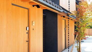 A row of wooden hotel rooms with black doors and a bamboo plant outside.