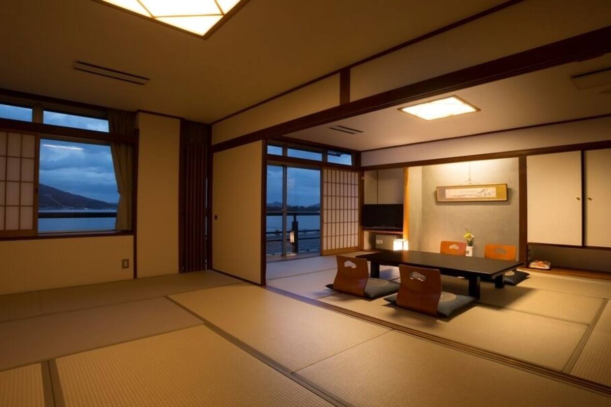 A traditional Japanese room with tatami flooring, sliding doors, and a low table with cushions.