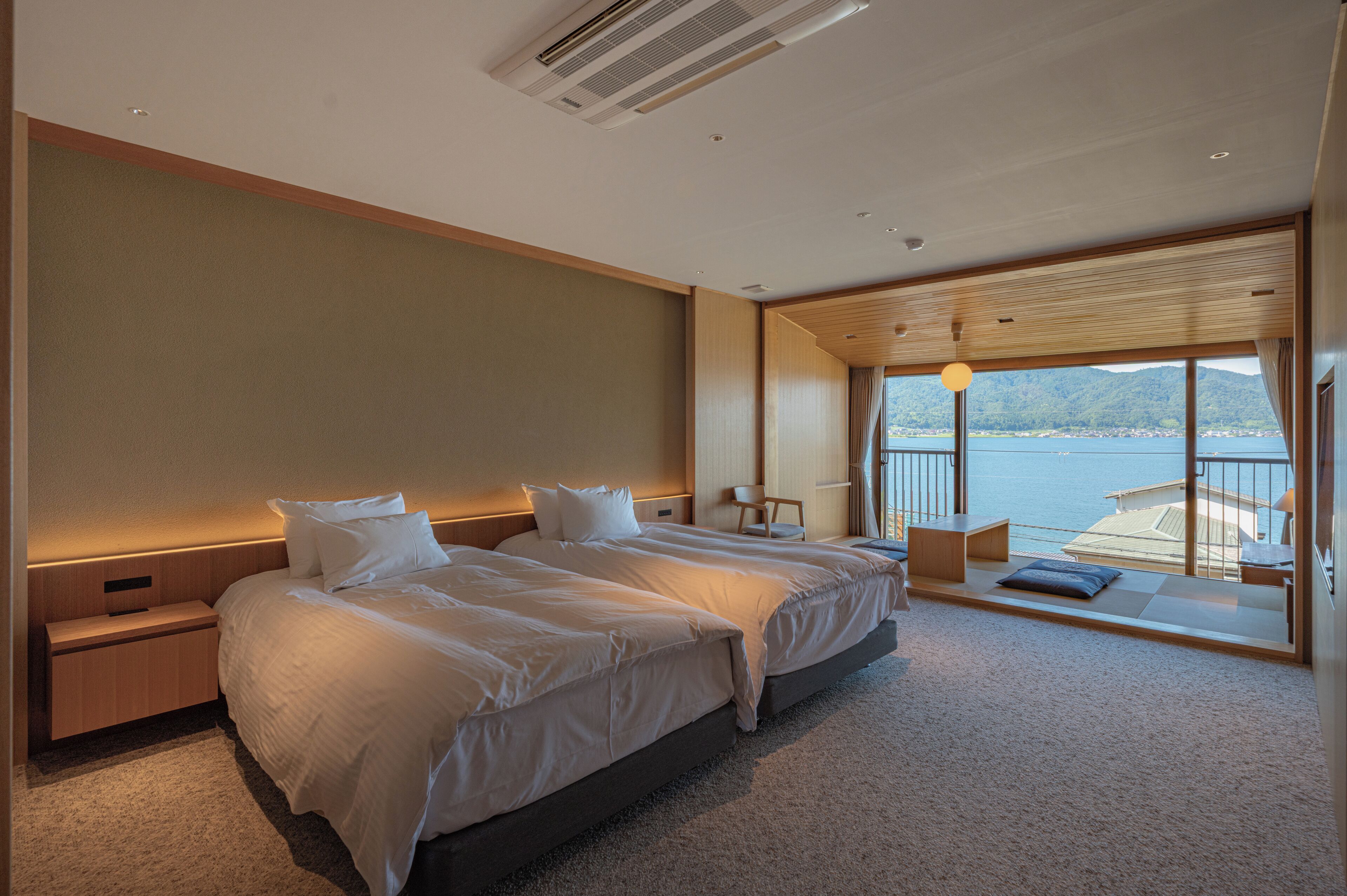 Une chambre d’hôtel moderne avec deux lits, une vue sur la mer et un balcon.