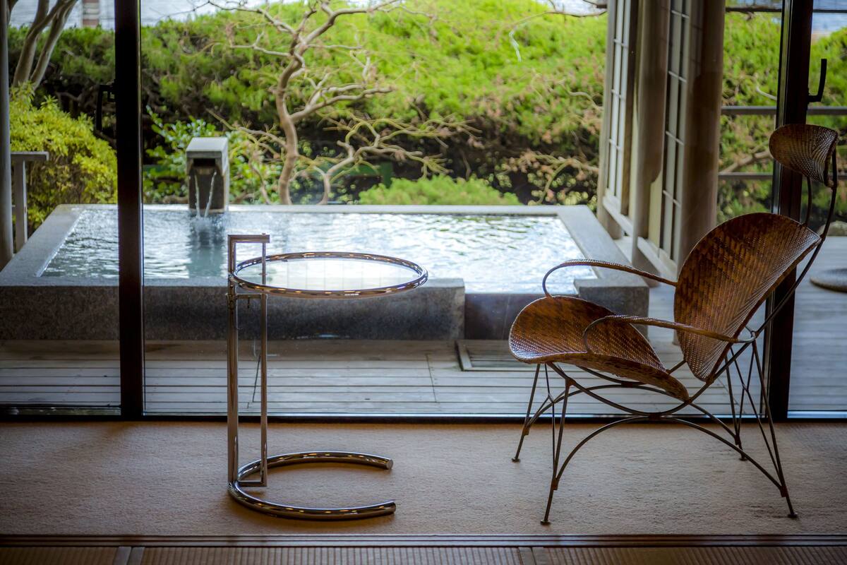 A room with a view of a water feature and greenery outside.