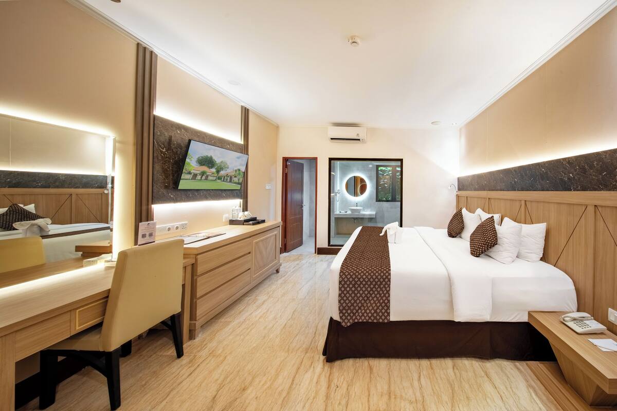A hotel room with a bed, desk, chair, and a TV mounted on the wall.