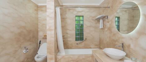 Un baño con bañera, inodoro, lavabo y espejo.