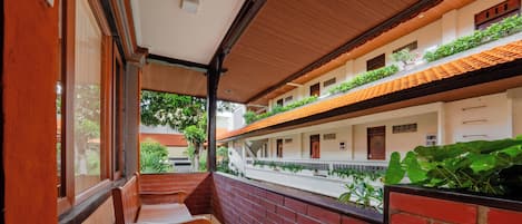 Un pasillo con un banco de madera, paredes de ladrillo y vistas al exterior con vegetación.