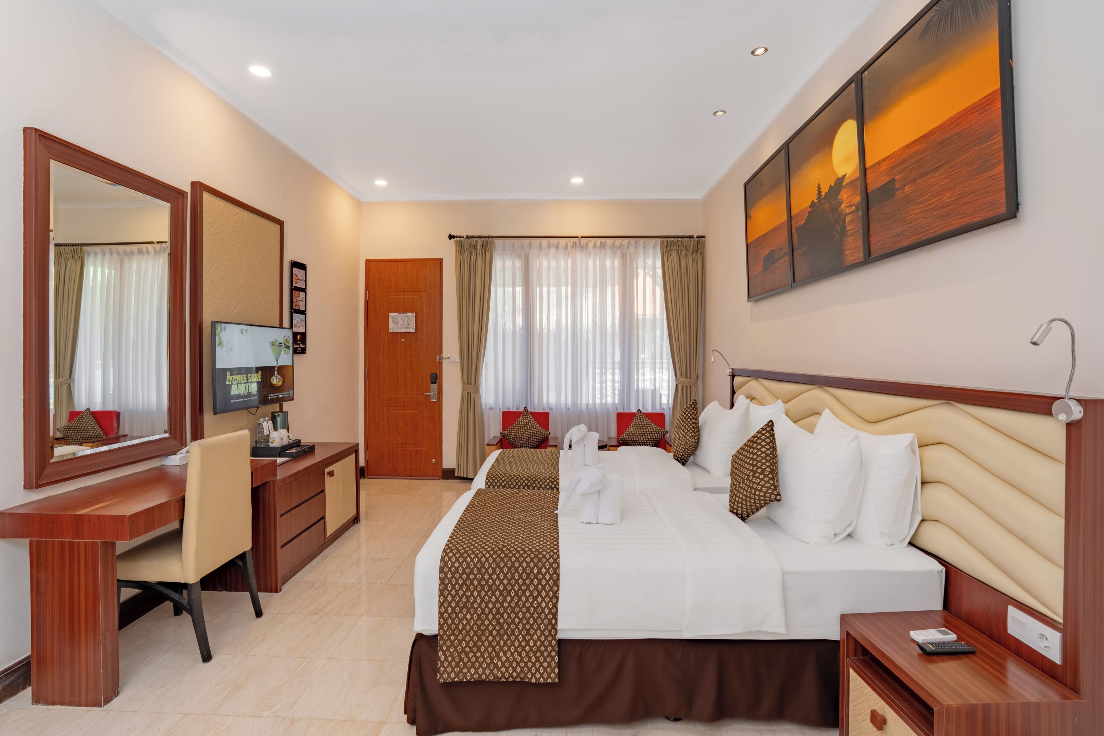 A hotel room with a bed, desk, chair, and a large painting on the wall.