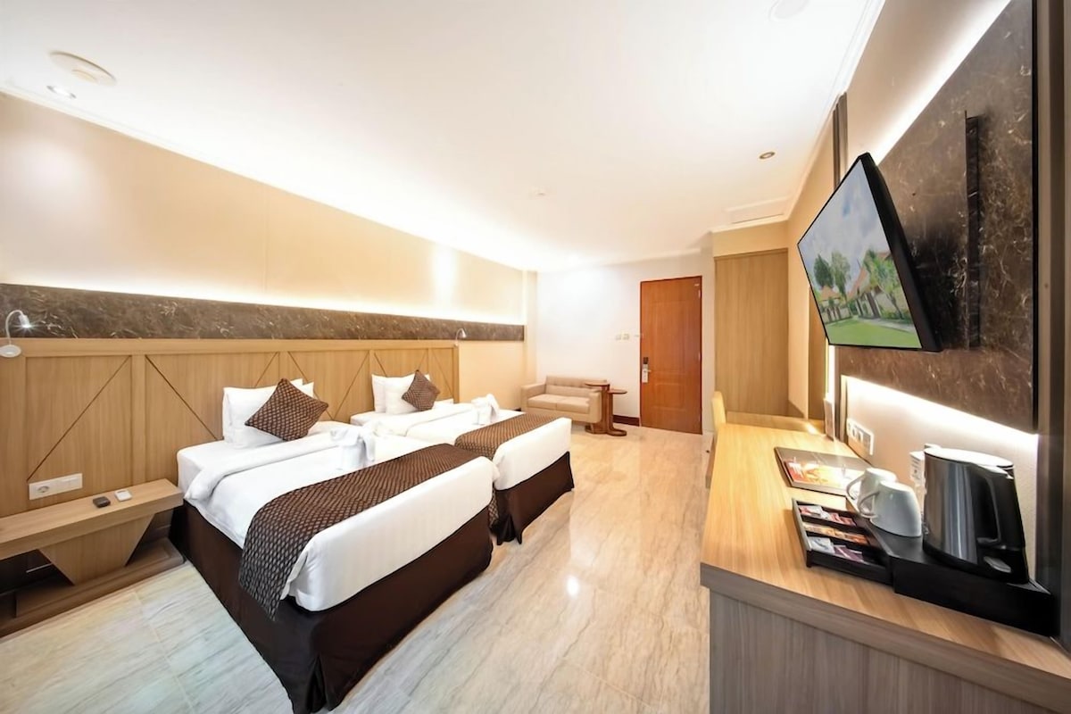 A hotel room with a bed, bedside tables, a TV, and a coffee machine.