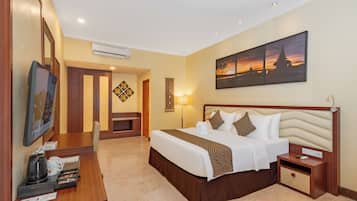 A hotel room with a bed, bedside table, lamp, and a painting of a sunset.