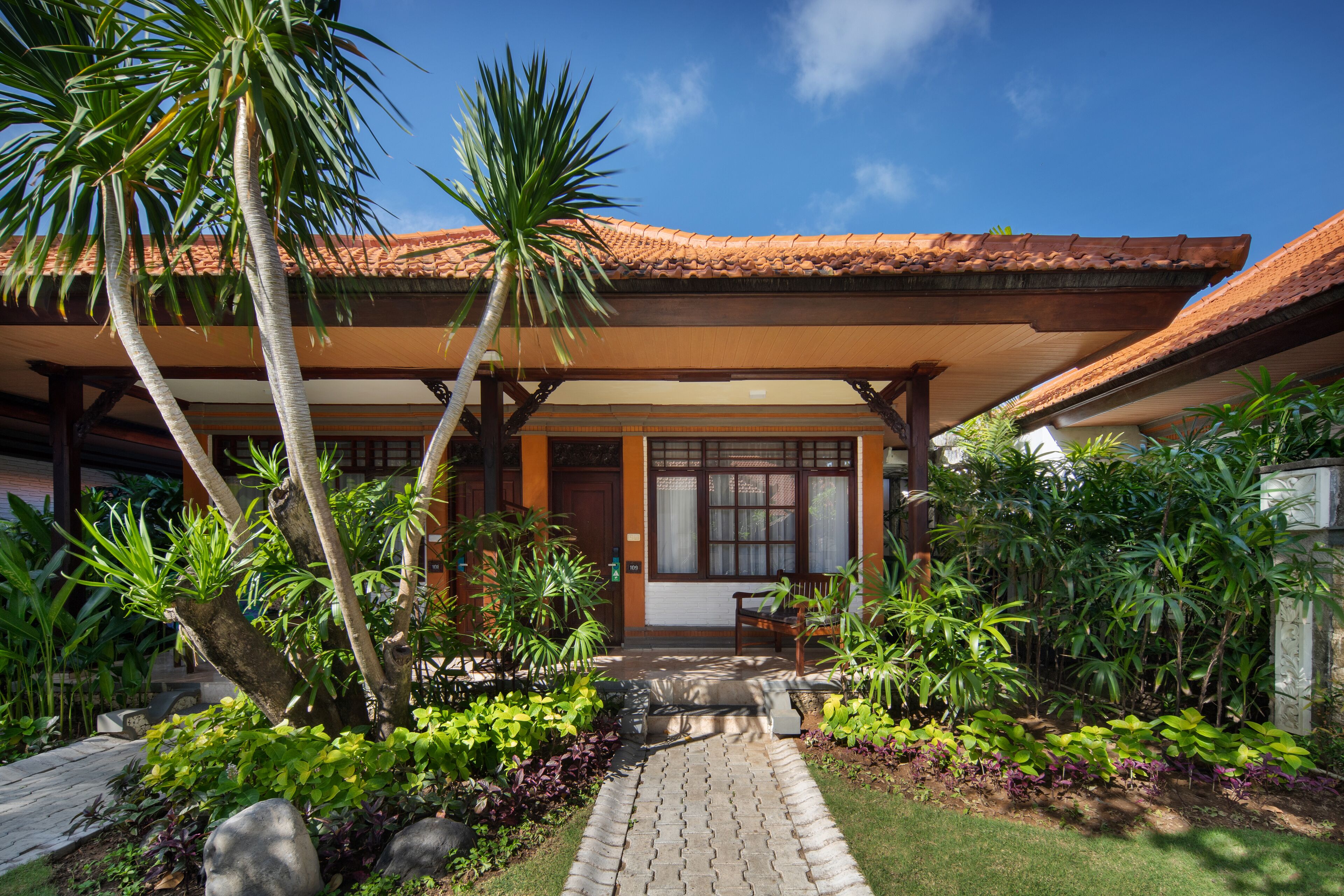 A house with a tiled roof, a covered porch, and a pathway leading to the entrance.