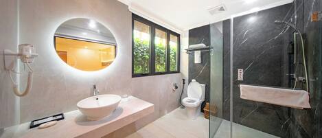 Une salle de bain moderne avec un grand miroir rond, un lavabo, des toilettes et une douche à parois de verre.