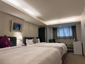 A hotel room with two beds, a desk, a chair, a small refrigerator, and a window with curtains. - If Inn (Taipei)
