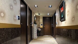 Un pasillo de hotel con paredes de mármol oscuro, papel tapiz estampado y suelo de baldosas.