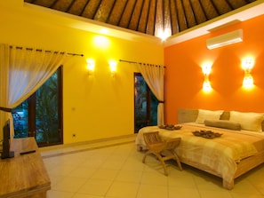 A bedroom with a bed, a chair, and a TV on a wooden table. - ArcoIris (Karangasem)