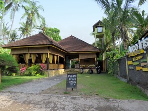 A building with a tiled roof and a signboard indicating a special offer for pizza and wine. - ArcoIris (Karangasem)
