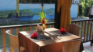 A dining table set with a vase of flowers, red napkins, and a menu. - ArcoIris (Karangasem)