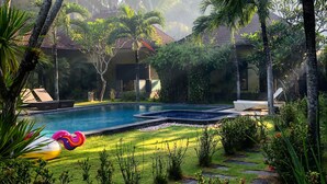 A pool area with a clear view of the surrounding lush greenery and palm trees. - ArcoIris (Karangasem)