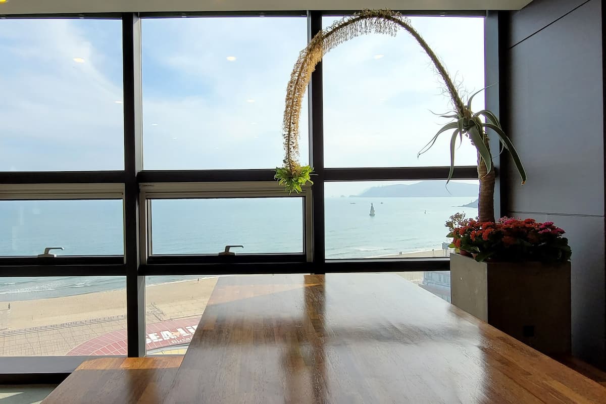 A room with a large window overlooking a beach and the sea.