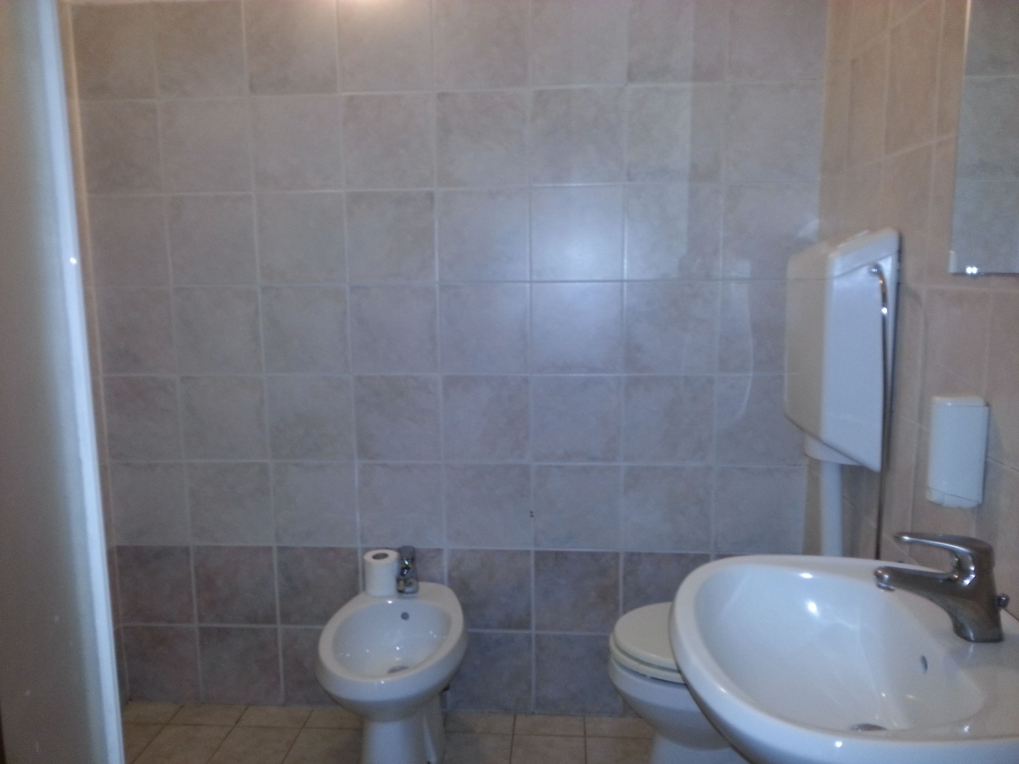 A bathroom with a bidet, toilet, and sink.