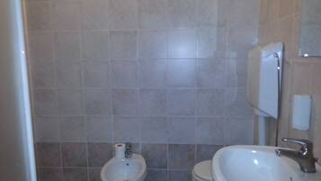 A bathroom with a bidet, toilet, and sink.