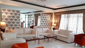 Una sala de estar moderna con sofás blancos, una mesa de centro de vidrio y cortinas estampadas.