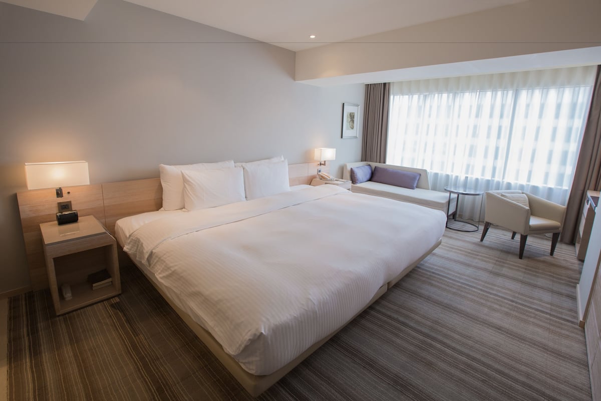 Una habitación de hotel con una cama grande, un escritorio, una silla y un sofá.