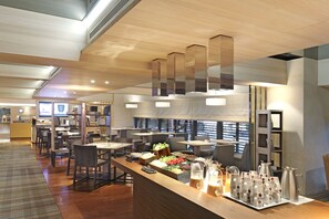 A modern restaurant with wooden flooring, a long counter with food and drinks, and a high ceiling with pendant lights. - HOTEL COZZI Minsheng Taipei (Taipei)