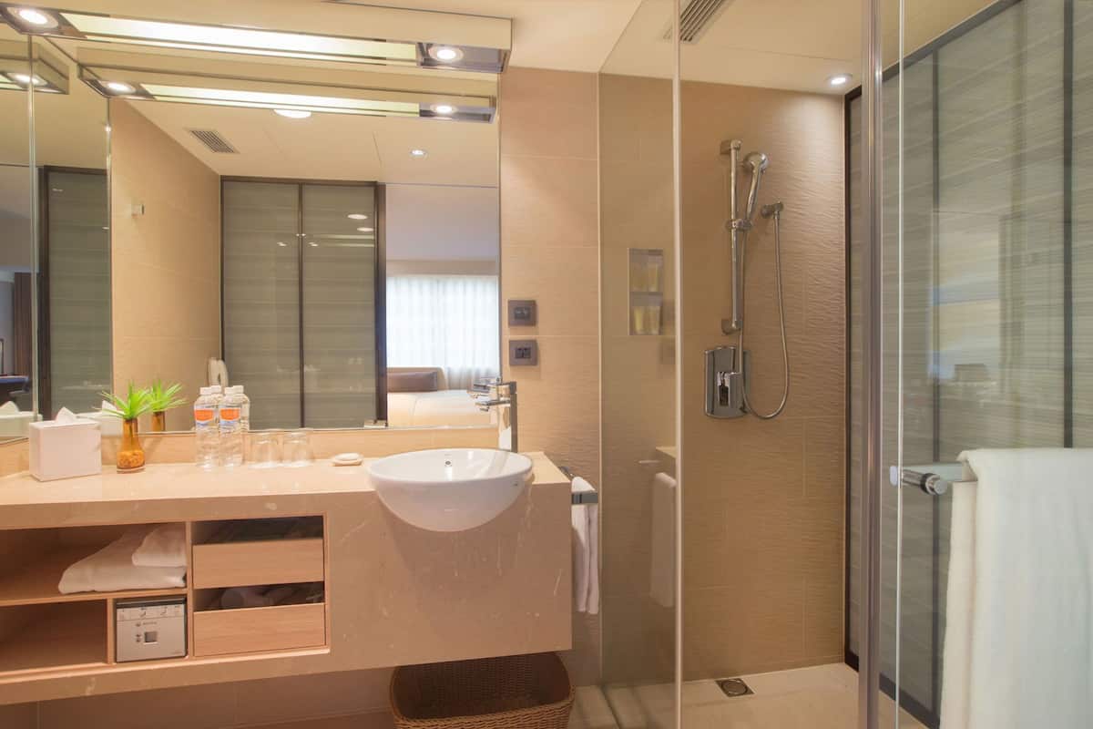 Un baño moderno con un espejo grande, un lavabo, ducha y cabina de ducha con mampara de vidrio.
