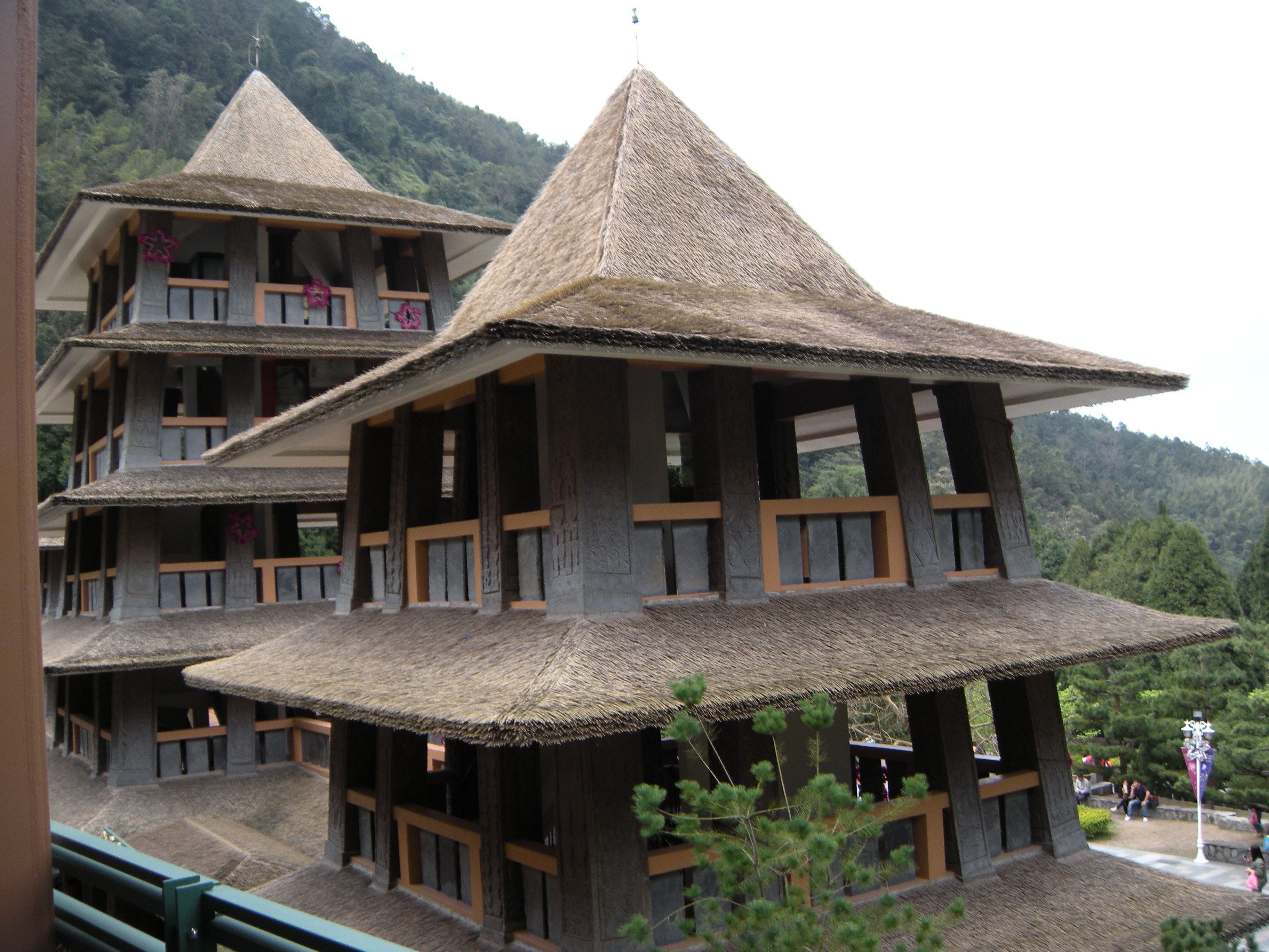 A multi-story building with a thatched roof and wooden balconies.