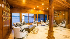 A spacious lobby with wooden walls, multiple seating areas, and large windows offering a view of the water. - LEALEA GARDEN HOTEL SUN MOON LAKE (Yuchi)