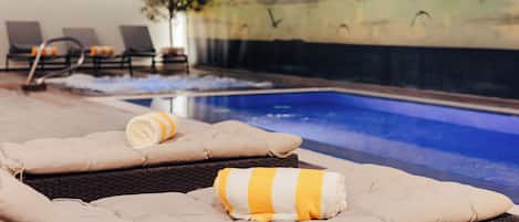Un área junto a la piscina con sillas de descanso y vista al agua.