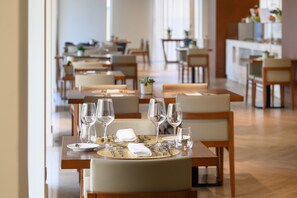 A dining area with tables set for a meal, including plates, cutlery, and wine glasses. - Melia Setubal (Setubal)