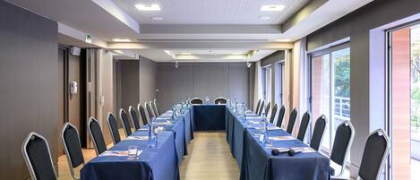 Un salón de conferencias con una larga mesa, sillas e iluminación empotrada en el techo.