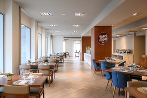 A modern restaurant with long tables and chairs, a wooden counter, and a sign that reads "Bistro & Tapas."