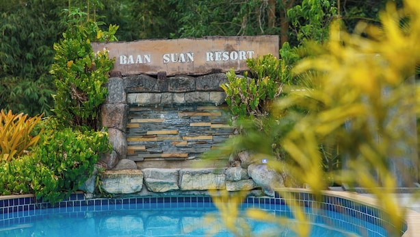 Señal para Baan Suan Resort, con un muro de piedra y una piscina al frente.