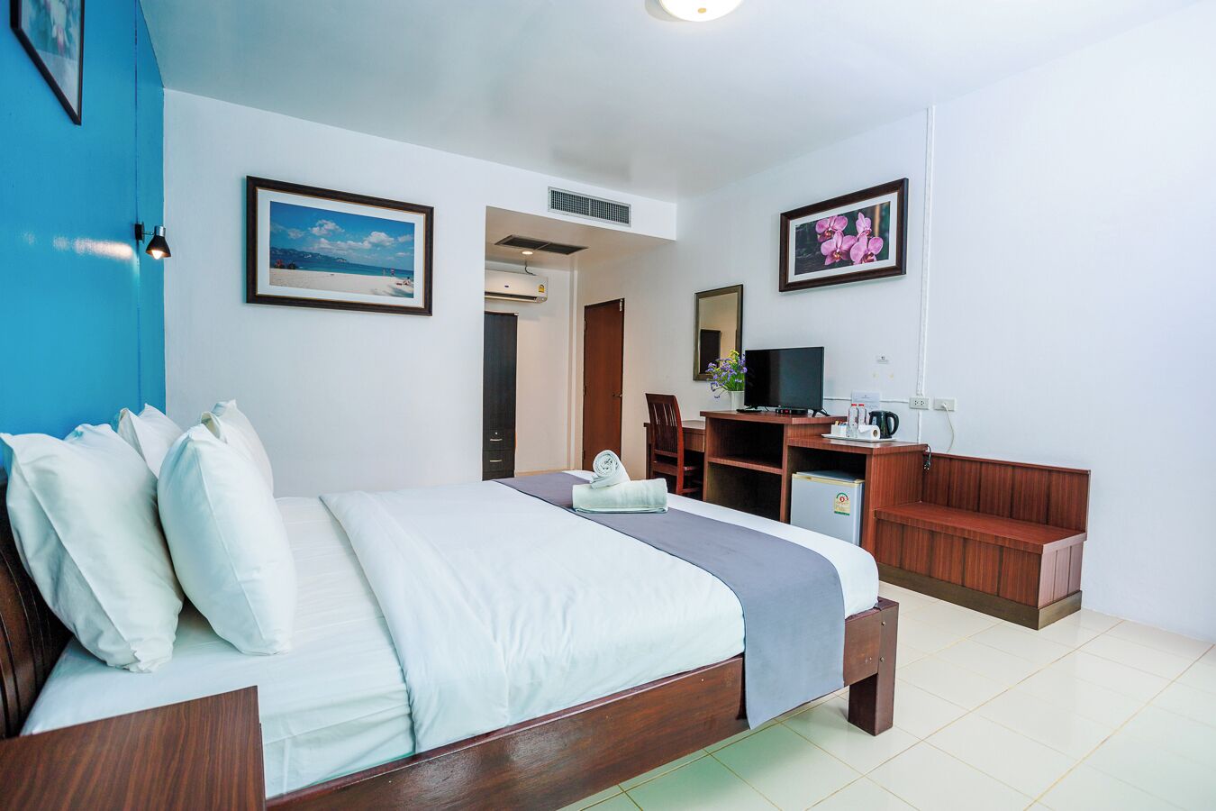 Ein Hotelzimmer mit Bett, Schreibtisch, Stuhl und Fernseher.