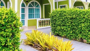 Un edificio de dos pisos con fachada verde, detalles blancos y varios ventanales en arco.