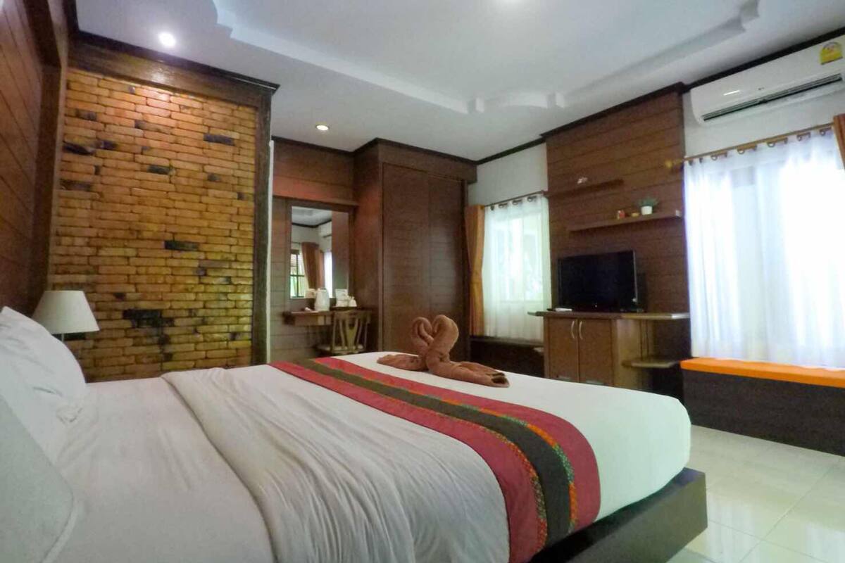 A hotel room with a large bed, a television, and a brick wall.