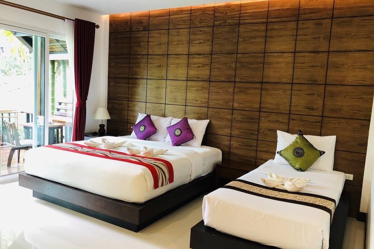 A modern hotel room with a large bed, a smaller bed, and a wooden headboard.